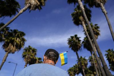 Zank Bennett, un voluntario de Estados Unidos, lleva una bandera de Ucrania en su gorra mientras ayuda a refugiados ucranianos que quieren solicitar asilo en su país, el 4 de abril de 2022, en Tijuana, México.Una coalición de voluntarios, en su mayoría de iglesias eslavas del oeste de Estados Unidos, guían a diario a cientos de refugiados desde el aeropuerto de la ciudad fronteriza mexicana de Tijuana a hoteles, iglesias y refugios, donde esperan entre dos y cuatro días para que las autoridades estadounidenses los admitan por causas humanitarias. (AP Foto/Gregory Bull)