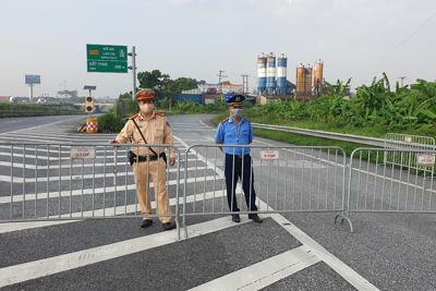 Policías montan guardia detrás de barricadas para controlar el tráfico en Hanoi, Vietnam, el sábado, 24 de julio del 2021. Vietnam anunció un encierro de 15 días en la capital  en medio de un aumento de los casos de coronavirus. (AP Foto/Hieu Dinh)