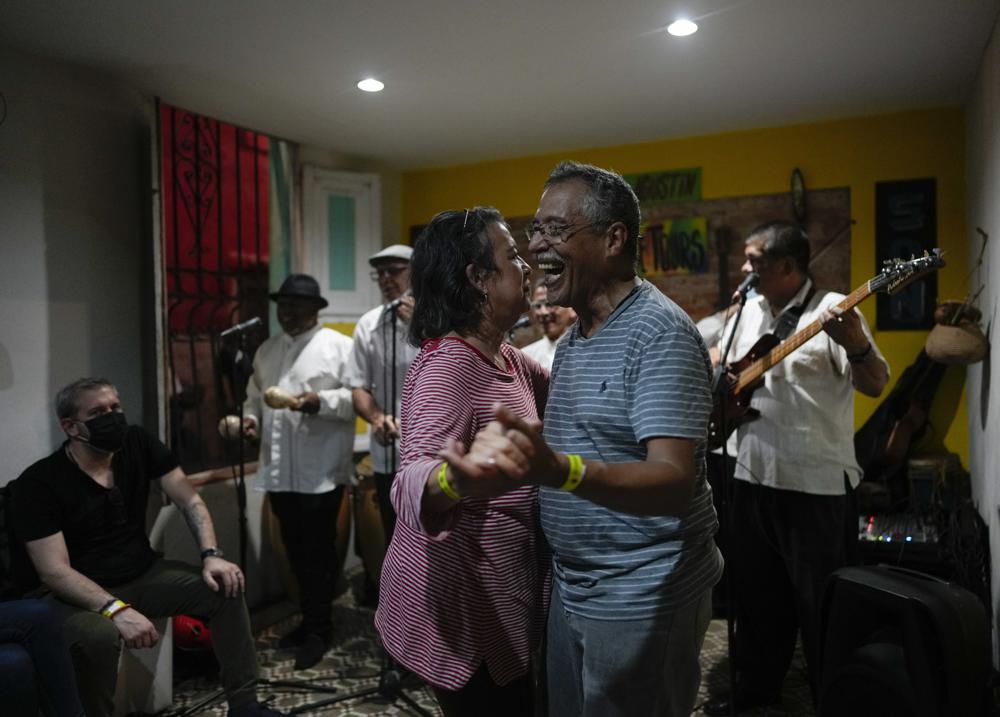 Una pareja baila al son de un grupo local conocido como "Son Mondondo" durante una gira organizada por Cumbe Tour por el barrio San Agustín de Caracas, Venezuela, el sábado 21 de agosto de 2021. Cumbe Tour trae turistas, tanto nacionales como extranjeros, a San Agustín para mostrarles cómo viven los venezolanos de menores ingresos en lo que solía ser uno de los barrios más peligrosos de la ciudad. (Foto AP/Ariana Cubillos)