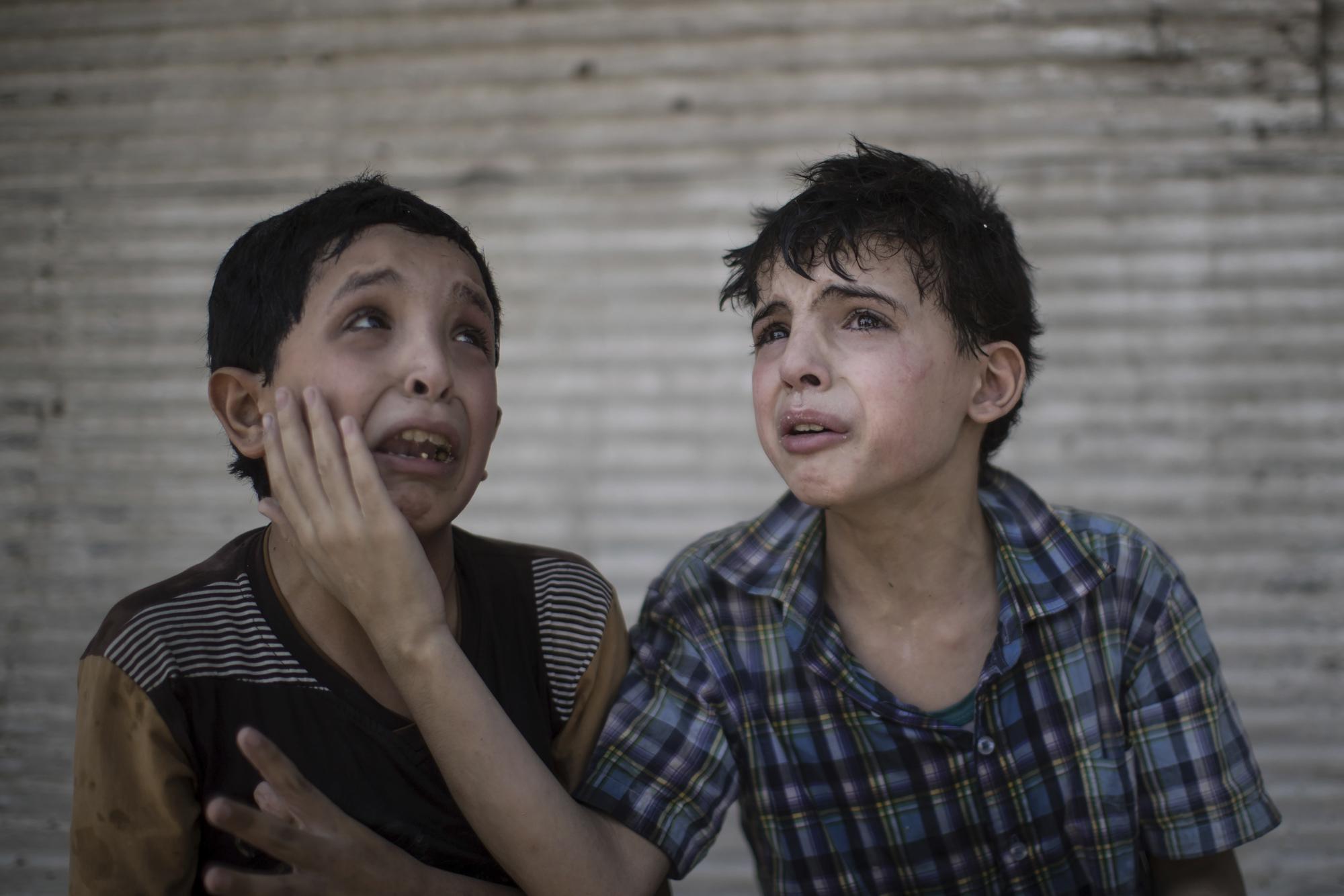 FILE - In this Saturday, June 24, 2017 file photo, Zeid Ali, 12, left, and Hodayfa Ali, 11, comfort each other after their house was hit and collapsed during fighting between Iraqi forces and Islamic State militants in Mosul, Iraq. The Ali cousins said some of their family members are still under the rubble. (AP Photo/Felipe Dana, File)