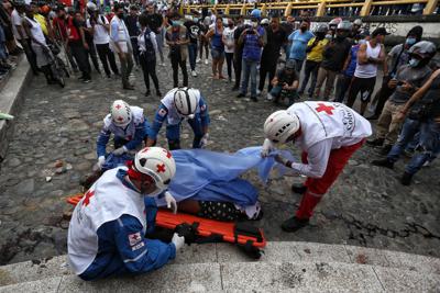 Paramédicos recogen el cuerpo de un hombre asesinado por manifestantes antigubernamentales al que acusaron de matar a un compañero manifestante que bloqueaba su paso en un control de carretera establecido por manifestantes en Cali, Colombia, el viernes 28 de mayo de 2021. (AP Foto/Andrés Gonzalez)