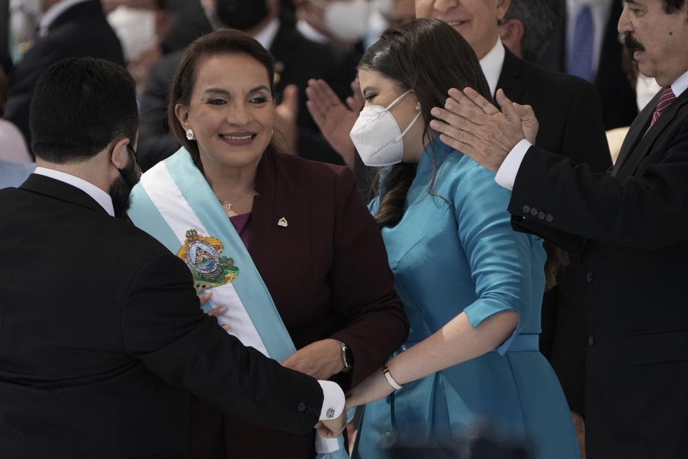 FILE - President Xiomara Castro smiles as she receives the presidential sash, as her husband former President Manuel Zelaya applauds during her inauguration ceremony, in Tegucigalpa, Honduras, Jan. 27, 2022. Castro signed a measure on Monday, April 25, 2022, to repeal a law that would allow the creation of special self-governing zones for foreign investors in Honduras. (AP Photo/Moises Castillo, File)