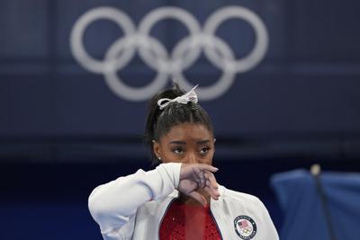 La estadounidense Simone Biles observa la actuación de otras gimnastas tras retirarse de la final por equipos de los Juegos de Tokio 2020 por una aparente lesión, el 27 de julio de 2021, en Tokio. (AP Foto/Ashley Landis)