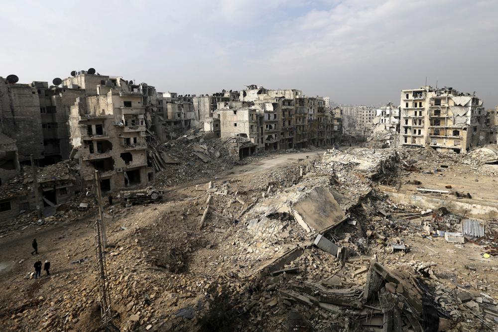 FILE - People walk through mounds of rubble which used to be high rise apartment buildings in the once rebel-held Ansari neighborhood in the eastern Aleppo, Syria, Friday, Jan. 20, 2017. For years, the people of Aleppo bore the brunt of bombardment and fighting when their city, once Syria's largest and most cosmopolitan, was one of the civil war's fiercest battle zones. Even that didn't prepare them for the new devastation and terror wreaked by this week's earthquake. (AP Photo/Hassan Ammar, File)