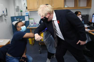 El primer ministro británico Boris Johnson saluda a Arzou Miah durante su visita al centro de vacunación Woodgrange GP Surgery en el este de Londres, el lunes 14 de noviembre de 2021. (Jeremy Selwyn, Pool Photo vía AP)