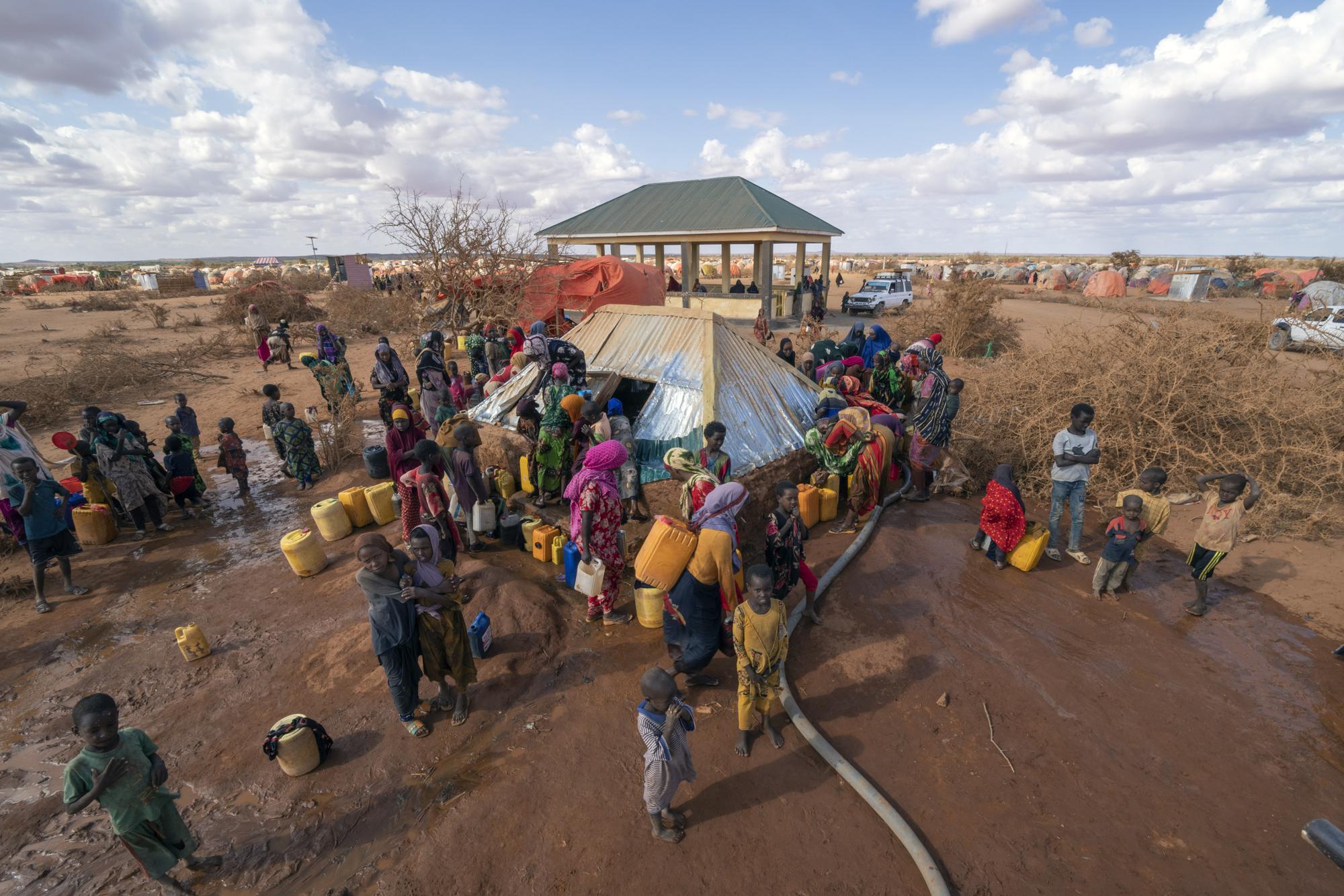 Water is distributed at a camp for displaced people on the outskirts of Dollow, Somalia on Tuesday, Sept. 20, 2022.  Somalia is in the midst of the worst drought anyone there can remember. A rare famine declaration could be made within weeks. Climate change and fallout from the war in Ukraine are in part to blame. (AP Photo/Jerome Delay)