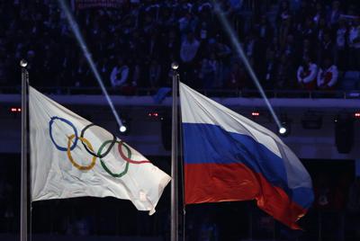 ARCHIVO - La bandera de Rusia (a la derecha) flamea junto a la de los Juegos Olímpicos durante la ceremonia de clausura de los Juegos de Invierno, en Sochi, el 23 de febrero de 2014. (AP Foto/Matthias Schrader)