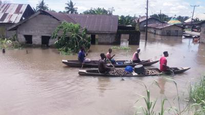 En esta imagen de archivo, varias personas transportan mercancías en canoa por las anegadas calles de una zona residencial tras las intensas lluvias, en Bayelsa, Nigeria, el 20 de octubre de 2022. (AP Foto/Reed Joshua, archivo)
