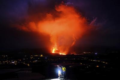 Dos personas caminan durante la noche mientras un volcán expulsa lava, en La Palma, Islas Canarias, el 25 de septiembre de 2021. (AP Foto/Daniel Roca)