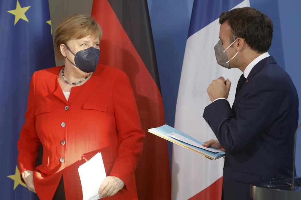 German Chancellor Angela Merkel, left, and French President Emmanuel Macron prepare to give a joint statement to journalists, at the chancellery in Berlin, Germany, Friday June 18, 2021. (Axel Schmidt/Pool via AP)