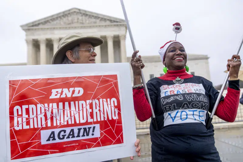Michael Martin of Springfield, Va., with UpVote Virginia, holds a sign that reads "End Gerrymandering Again!" and speaks with Nadine Seiler of Waldorf, Md., in front of the Supreme Court in Washington, Wednesday, Dec. 7, 2022, as the Court hears arguments on a new elections case that could dramatically alter voting in 2024 and beyond. The case is from highly competitive North Carolina, where Republican efforts to draw congressional districts heavily in their favor were blocked by a Democratic majority on the state Supreme Court. (AP Photo/Andrew Harnik)