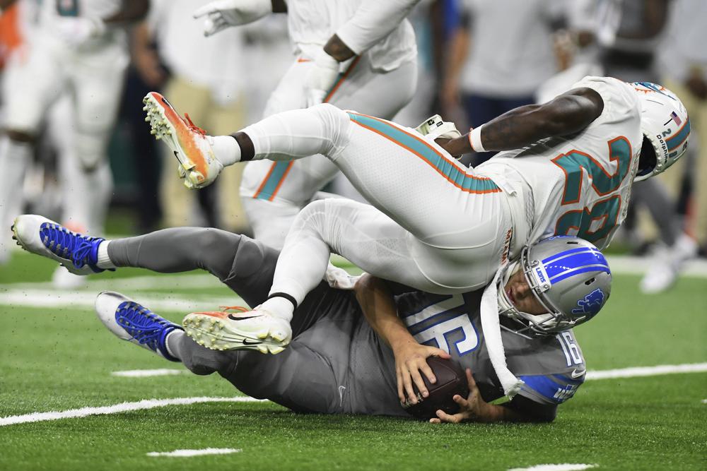 Miami Dolphins cornerback Kader Kohou (28) falls over Detroit Lions quarterback Jared Goff (16) during the second half of an NFL football game, Sunday, Oct. 30, 2022, in Detroit. (AP Photo/Lon Horwedel)