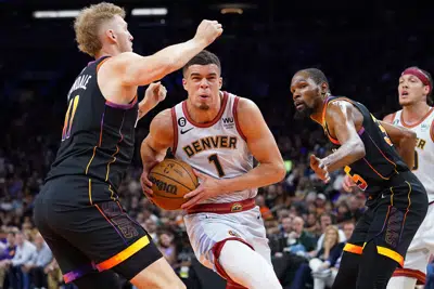 El alero de los Denver Nuggets Michael Porter Jr. (1) conduce entre el centro de los Phoenix Suns, Jock Landale, a la izquierda, y el alero Kevin Durant, a la derecha, durante la segunda mitad del Juego 3 de un partido de semifinales de la Conferencia Oeste de baloncesto de la NBA, el viernes 5 de mayo de 2023, en Phoenix. Los Suns derrotaron a los Nuggets 121-114. (AP Photo/Matt York)