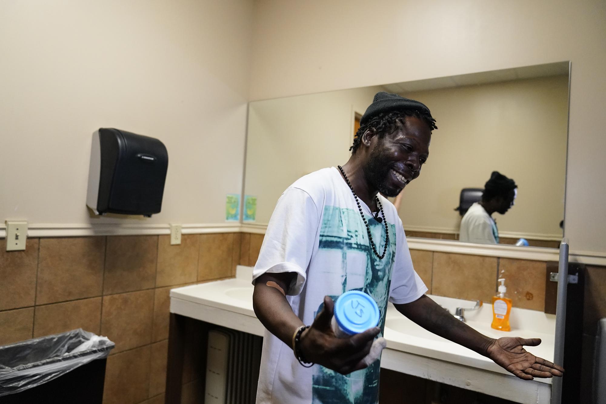 Jerry Simmons, 49, holds a cup just before he takes a drug test in a restroom in St. Louis on Thursday, May 20, 2021. “I just want to be a normal person back in society, working, living, loving, playing with my grandkids, making my kids be proud of me,” said Simmons, who’s been addicted for 30 years, homeless and in and out of prisons. (AP Photo/Brynn Anderson)