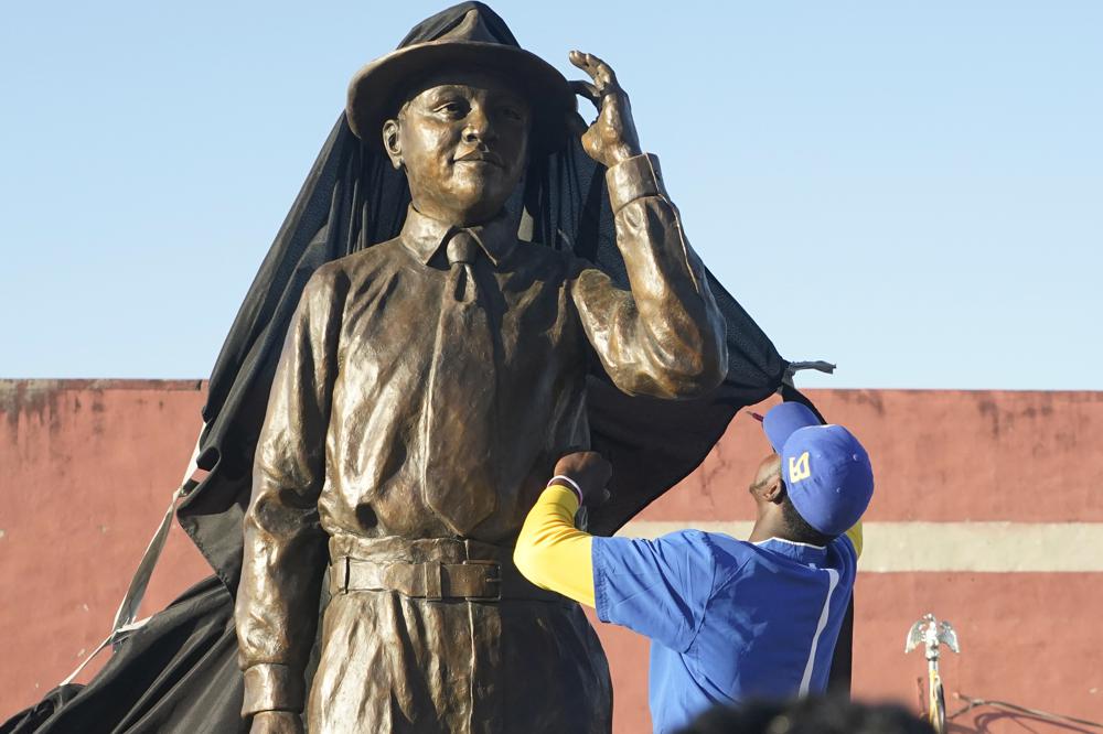 An event worker removes the tarp of the Emmett Till statue during its unveiling, Friday, Oct. 21, 2022 in Greenwood, Miss. Till was a 14-year-old African American boy who was abducted, tortured, and lynched, Aug. 28,1955, after being accused of offending a white woman, in her family's grocery store in Money. (AP Photo/Rogelio V. Solis)