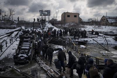 ARCHIVO - Los ucranianos cruzan un camino improvisado bajo un puente destruido mientras huyen de Irpin, en las afueras de Kiev, Ucrania, el martes 8 de marzo de 2022. (AP Foto/Felipe Dana)