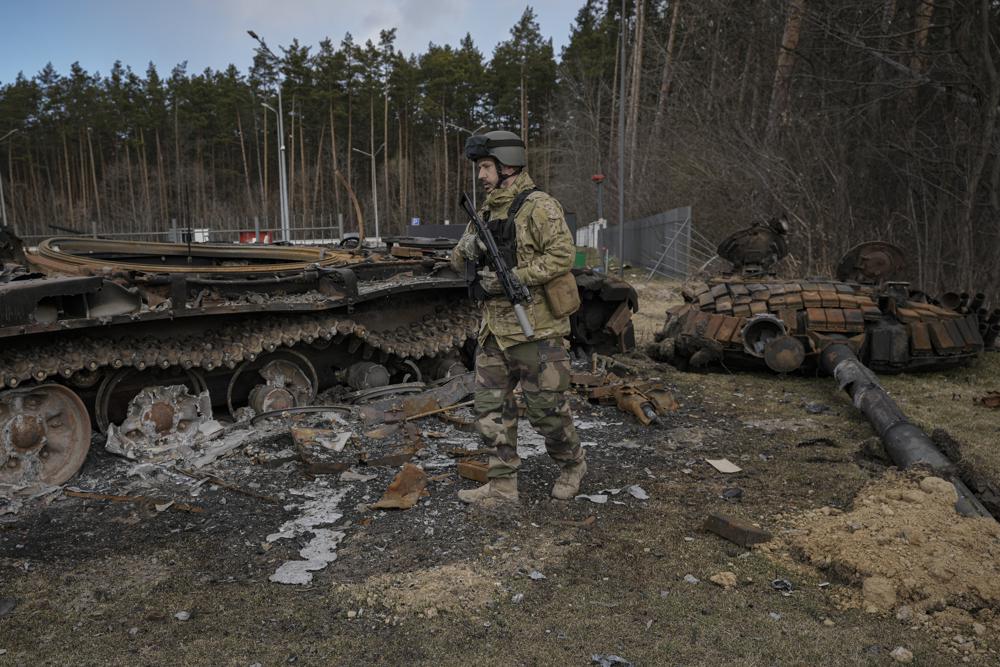 FILE - A Ukrainian serviceman walks next to the wreck of a Russian tank in Stoyanka, Ukraine, March 27, 2022. Russia is bracing up for a massive new offensive in eastern Ukraine, hoping to reverse its fortunes on the battlefield after a catastrophic start of the invasion. (AP Photo/Vadim Ghirda, File)
