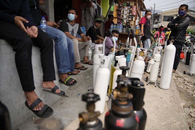 People queue up to refill their oxygen tanks at a filling station in Jakarta, Indonesia, Monday, July 5, 2021. Parts of Indonesia lack oxygen supplies as the number of critically ill COVID-19 patients who need it increases, the nation's pandemic response leader said Monday, after dozens of sick people died at a public hospital that ran out of its central supply. (AP Photo/Dita Alangkara)