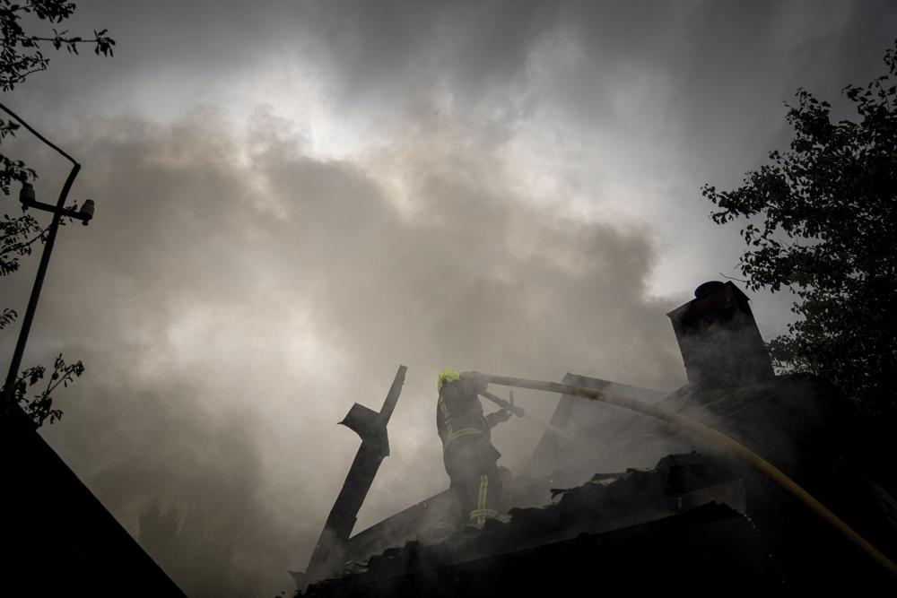 A rescue worker puts out the fire on a destroyed house after a Russian attack in a residential neighborhood in downtown Kharkiv, Ukraine, on Monday, July 11, 2022.  The top official in the Kharkiv region said Monday the Russian forces launched three missile strikes on the city targeting a school, a residential building and warehouse facilities. (AP Photo/Evgeniy Maloletka)