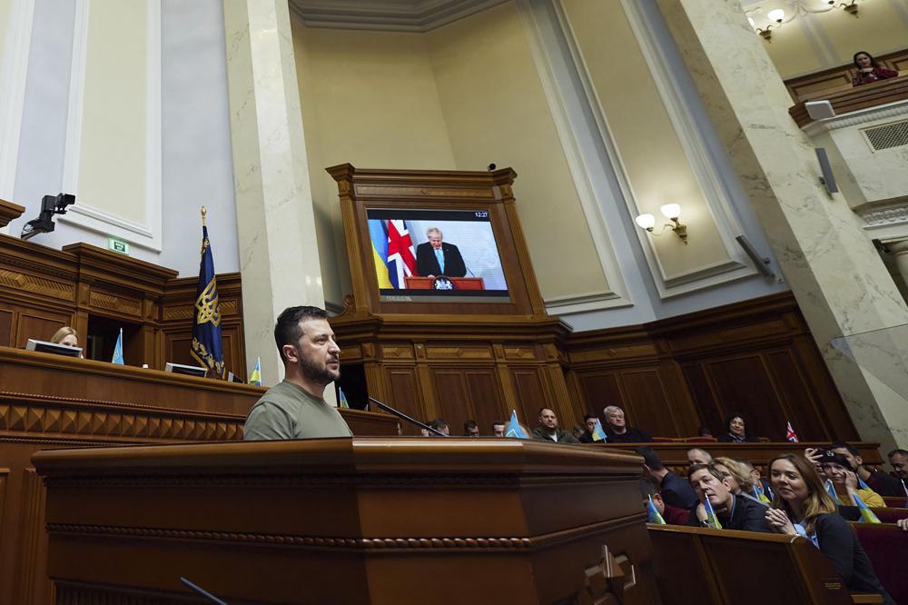 En esta foto difundida por la Oficina de la Presidencia ucraniana, el presidente ucraniano Volodymyr Zelenskyy habla ante el parlamento mientras una pantalla muestra la imagen del primer ministro británico Boris Johnson, en Kiev, Ucrania, martes 3 de mayo de 2022. (Oficina de la Presidencia vía AP)