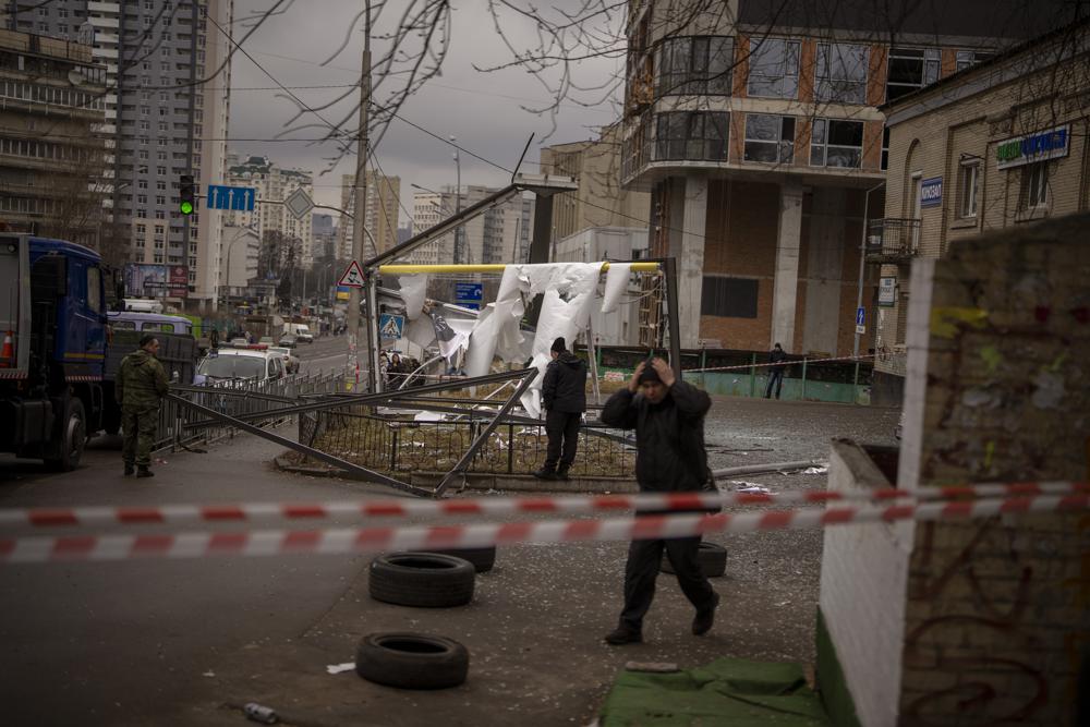 Police officers inspect an area after an apparent Russian strike in Kyiv Ukraine, Thursday, Feb. 24, 2022. (AP Photo/Emilio Morenatti