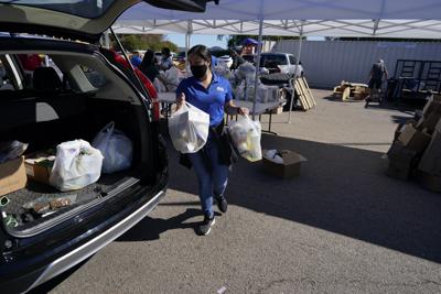 Una voluntaria carga alimentos en una camioneta en un centro de distribución de comida para soldados necesitados de las fuerzas armadas de EEUU, manejado por la Asociación Cristiana de Jóvenes en San Diego el 28 de octubre del 2021. (AP Photo/Gregory Bull)