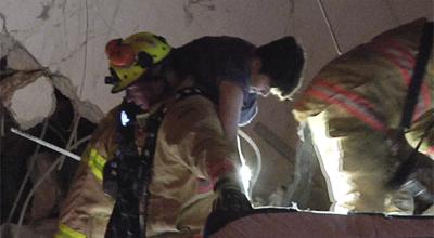 Imagen tomada de un video proporcionado por ReliableNewsMedia de bomberos rescatando a un sobreviviente del condominio Champlain después de que se derrumbara parcialmente en Surfside, Florida, el jueves 24 de junio de 2021. (ReliableNewsMedia vía AP)