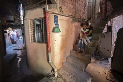 Ana Carolina Silva, quien perdió su trabajo durante la pandemia de COVID-19, posa con su hija Cataleia fuera de su casa en la favela Paraisopolis de Sao Paulo, Brasil, el lunes 24 de mayo de 2021. (AP Foto/Andre Penner)