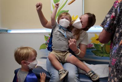 Jen Maddock y su hijo Will, de 23 meses, levantan los puños en celebración después que el pequeño recibió la vacuna contra el COVID-19 en Southwest Pediatrics el miércoles 22 de junio de 2022 en St. Louis. (Robert Cohen/St. Louis Post-Dispatch vía AP)