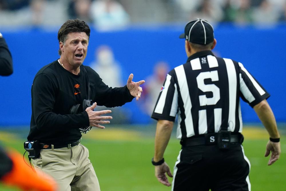 FILE - Oklahoma State head coach Mike Gundy, left, argues a call with an official during the first half of the Fiesta Bowl NCAA college football game against Notre Dame, Jan. 1, 2022, in Glendale, Ariz. Oklahoma State has boosted Gundy’s salary to $7.5 million for the 2022 calendar year. (AP Photo/Ross D. Franklin, File)