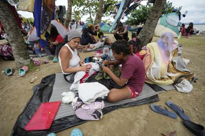 Migrantes venezolanos descansan en la playa mientras esperan un bote para dirigirse a Acandí desde Necoclí, Colombia, el jueves 13 de octubre de 2022. Algunos venezolanos están reconsiderando su viaje a Estados Unidos después de que el gobierno de Joe Biden anunciara el 12 de octubre que los venezolanos intenten cruzar por tierra la frontera sur serán devueltos inmediatamente a México sin derecho a solicitar asilo. (Foto AP/Fernando Vergara)