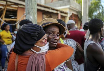 Dos personas se abrazan llorando el 15 de agosto del 2021 en Les Cayes, Haití, mientras buscan desaparecidos entre los escombros de una casa destruida por un terremoto que golpeó el día previo. (AP Photo/Joseph Odelyn)