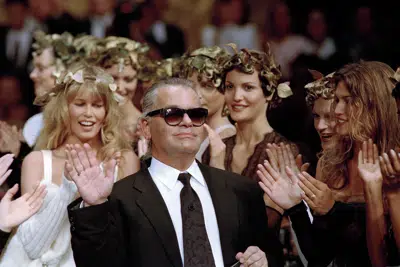 ARCHIVO - El diseñador de moda alemán Karl Lagerfeld agradece el aplauso de sus modelos al final del desfile que diseñó para la casa de moda francesa Chanel, para la colección de alta costura Otoño-Invierno 1993-94 en París, el 20 de julio de 1993. (AP Photo/Lionel Cironneau, archivo)