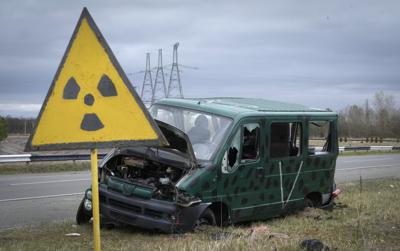 Un letrero de peligro de radiación cerca de un vehículo dañado con una letra V, indicando que era utilizado por el ejército ruso, cerca de la planta fuera de servicio en Chérnobil, Ucrania, el 16 de abril de 2022. (AP Foto/Efrem Lukatsky)