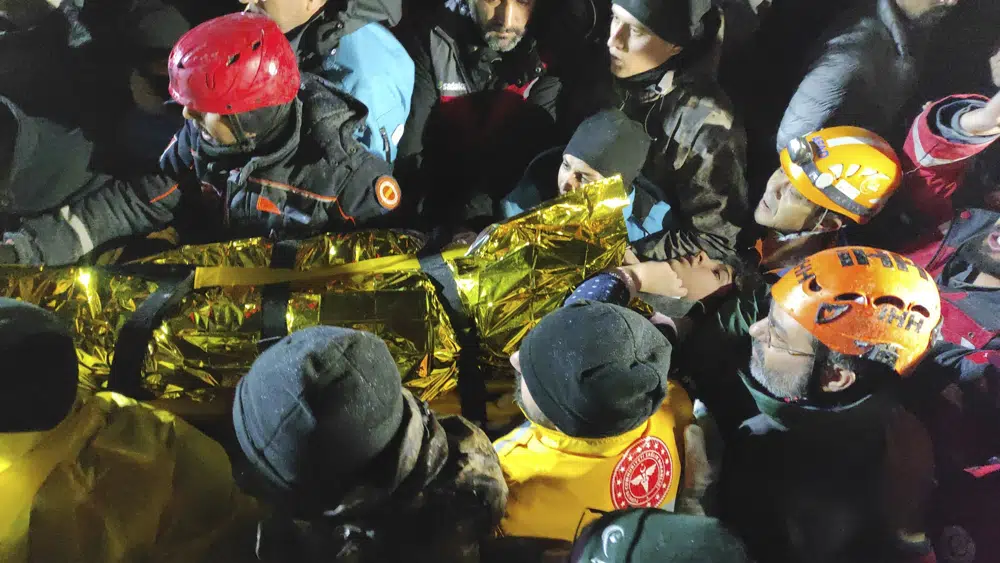 Rescue workers and medics carry a young woman they have rescued from the debris of a collapsed building in Sanliurfa, southern Turkey, late Monday, Feb. 6, 2023. Rescuers in Turkey and war-ravaged Syria searched through the frigid night into Tuesday, hoping to pull more survivors from the rubble after a powerful earthquake. (IHA via AP)