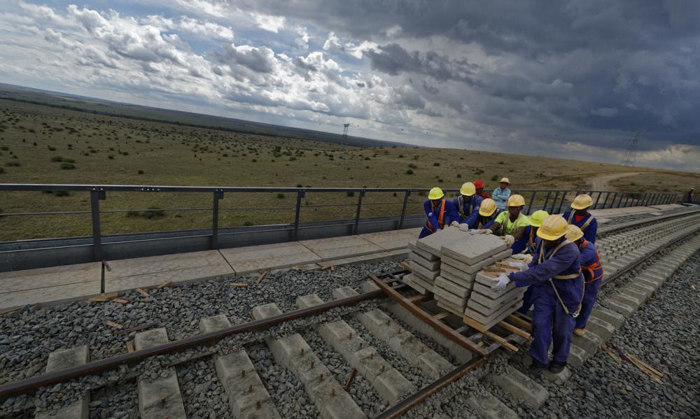 FILE - Kenyan laborers work to finish the construction of an existing bridge that goes across a corner of Nairobi National Park in Nairobi, Kenya on Wednesday, Nov. 23, 2016, as part of a Chinese-built railway project. An Associated Press analysis of a dozen countries most indebted to China - including Pakistan, Kenya, Zambia and Mongolia - found payments on the debt are consuming an ever-greater amount of the tax revenue needed to provide basic services. (AP Photo/Ben Curtis, File)