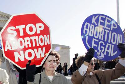 ARCHIVO - En esta foto de archivo del 30 de noviembre de 2005, activistas a favor y en contra del aborto se manifiestan frente a la Corte Suprema en Washington. La leyenda en el cartel rojo dice "detener el aborto ya". La del cartel azul, "mantener el aborto legal". Según una nueva encuesta AP-NORC difundida el viernes 25 de junio de 2021, el 61% dice que el aborto debe ser legal durante el primer trimestre del embarazo, pero el 65% dijo que debe ser ilegal en el 2do trimestre. (AP Foto/Manuel Balce Ceneta)