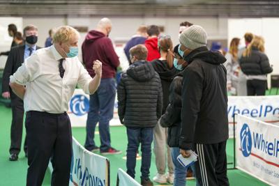 El primer ministro británico Boris Johnson, izquierda, visita un centro de vacunación en el estadio Stoke Mandeville de Aylesbury, Inglaterra, el lunes 3 de enero de 2022. (Steve Parsons/Pool vía AP)