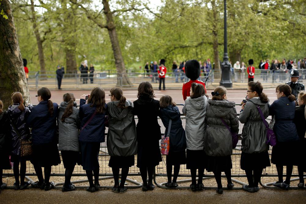 School girls wait to catch a glimpse of Britains Queen Elizabeth II as she processes along the Mall in a carriage en route to Buckingham Palace after delivering her speech in the State Opening of Parliament in London, May 9, 2012. (Photo: Matt Dunham/AP)