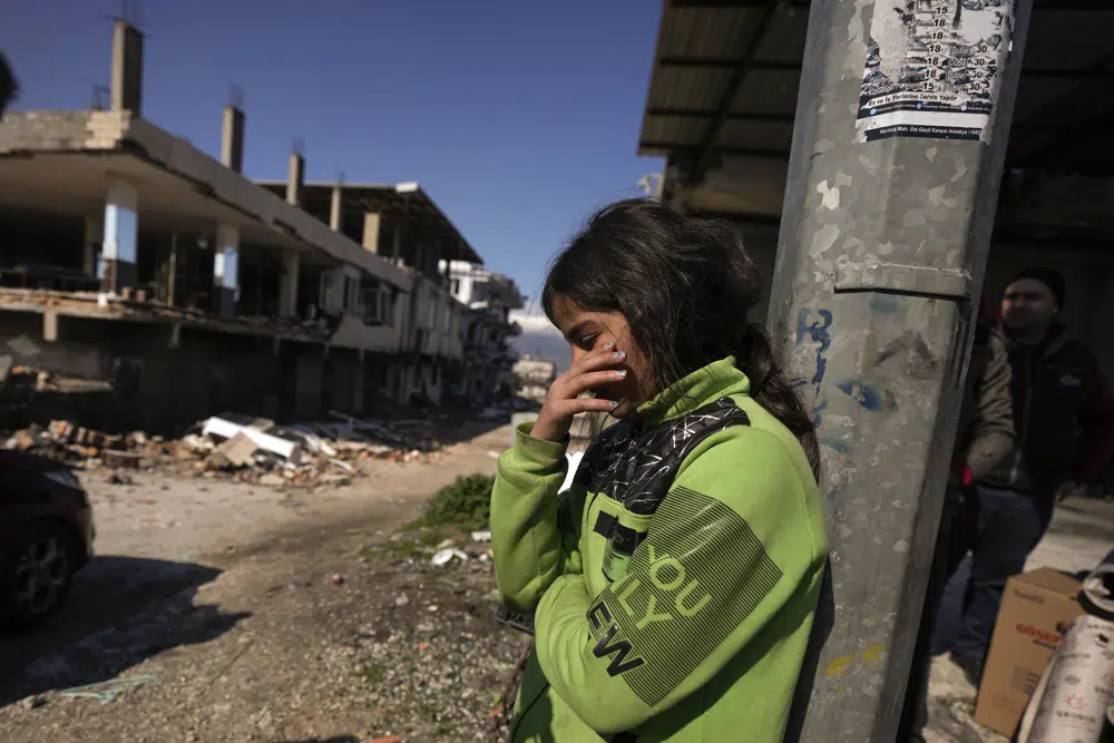 Una niña junto a edificios destruidos en Antakya, sur de Turquía, el miércoles 8 de febrero de 2023. Los equipos de rescate trabajaron toda la noche hasta el miércoles, sacando más cuerpos de los escombros de miles de edificios derribados en Turquía y Siria por un catastrófico terremoto.  (Foto AP/Khalil Hamra)