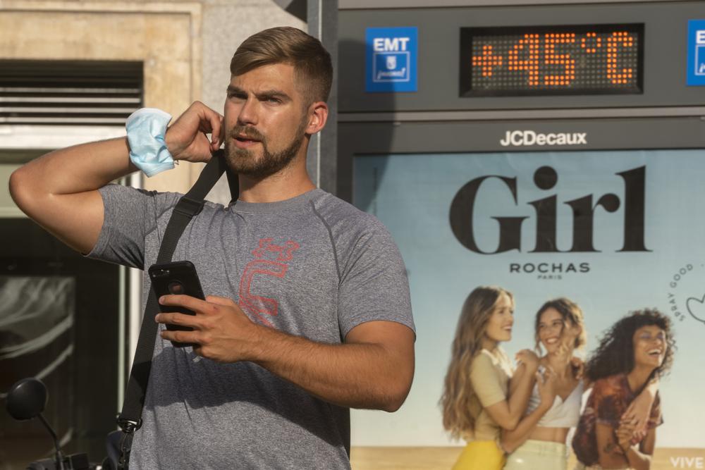 Un hombre camina frente a un termómetro que marca 45 grados Celsius durante una ola de calor en Madrid, España, el viernes 13 de agosto de 2021. (AP Foto/Andrea Comas)