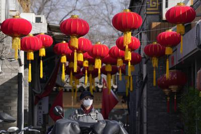 Una persona con mascarilla camina bajo faroles rojos colocados por el Año Nuevo Lunar en Beijing, China, el lunes 7 de febrero de 2022.  (AP Foto/Ng Han Guan)