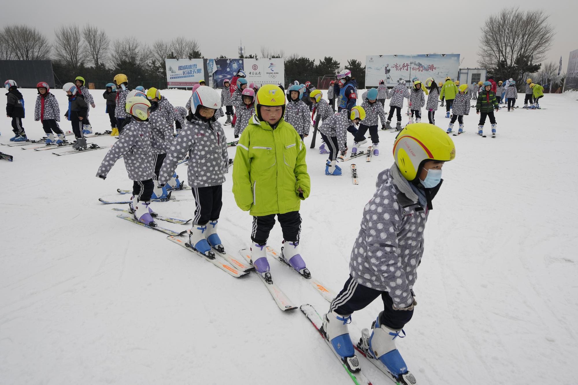 School children learning to ski take to the slope at the Vanke Shijinglong Ski Resort in Yanqing on the outskirts of Beijing, China, Thursday, Dec. 23, 2021. The Beijing Winter Olympics is tapping into and encouraging growing interest among Chinese in skiing, skating, hockey and other previously unfamiliar winter sports. It's also creating new business opportunities. (AP Photo/Ng Han Guan)