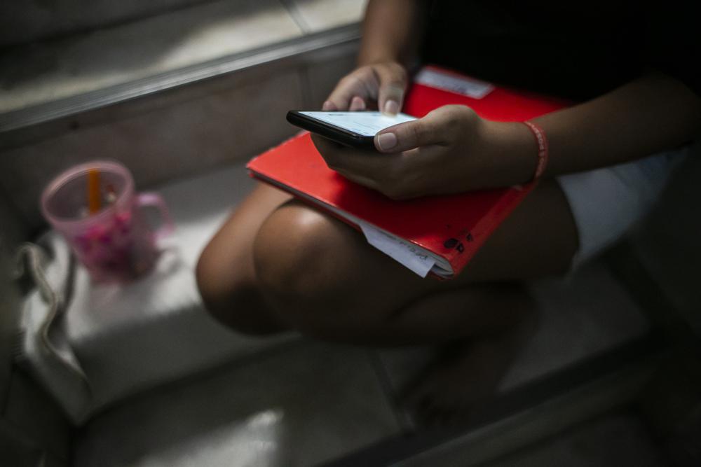 FILE – In this Sept. 29, 2021, file photo, Marcela Rodrigues, 14, looks at her cellphone, in Rio de Janeiro, Brazil. From complaints whistleblower Frances Haugen has filed with the SEC, along with redacted internal documents obtained by The Associated Press, the picture of the mighty Facebook that emerges is of a troubled, internally conflicted company, where data on the harms it causes is abundant, but solutions are halting at best. (AP Photo/Bruna Prado, File)