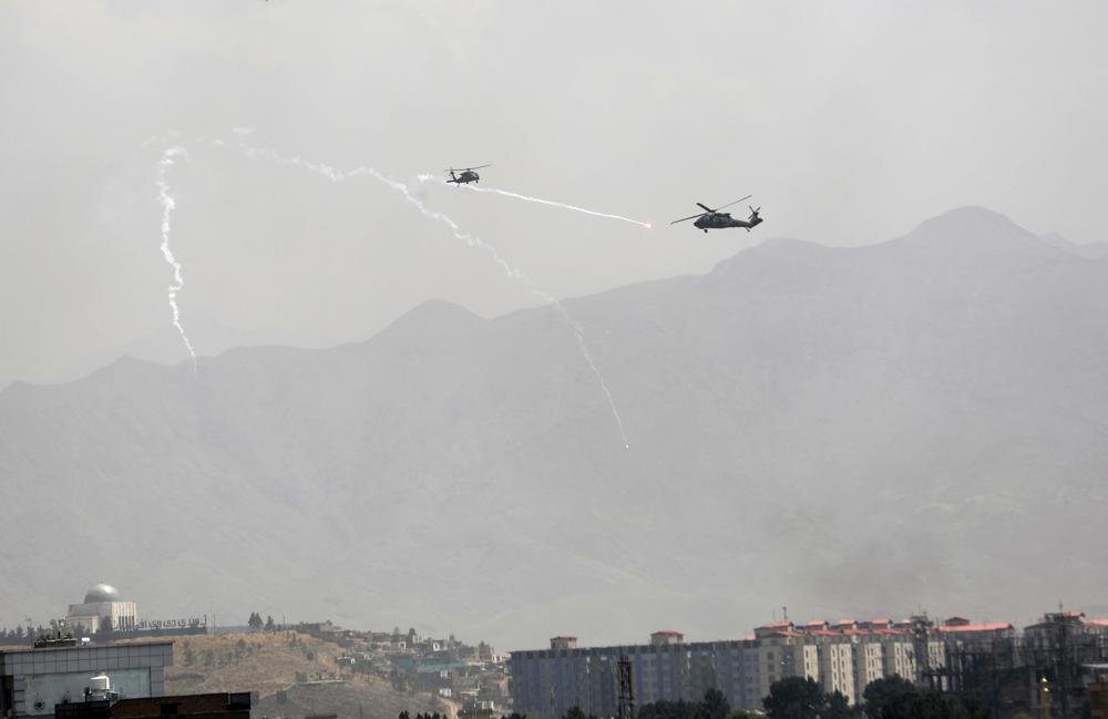 Anti-missile decoy flares are deployed as U.S. Black Hawk military helicopters fly over the city of Kabul, Afghanistan, Sunday, Aug. 15, 2021. Taliban fighters entered the outskirts of the Afghan capital on Sunday and said they were awaiting a “peaceful transfer” of the city after promising not to take it by force, but amid the uncertainty panicked workers fled government offices and helicopters landed at the U.S. Embassy. (AP Photo/Rahmat Gul)