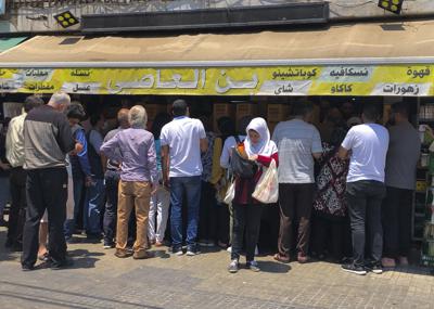 Gente se aglomera frente a una tienda para comprar café ante el temor de que haya escasez, en Beirut, Líbano, 23 de junio de 2021.  (AP Foto/Hussein Malla)