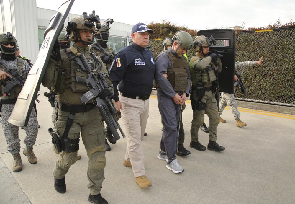 In this photo released by the Colombian Presidential Press Office, police escort Dairo Antonio Usuga, center, also known as Otoniel, leader of the violent Clan del Golfo cartel prior to his extradition to the U.S., at a military airport in Bogota, Colombia, Wednesday, May 4, 2022. (Colombian presidential press office via AP)