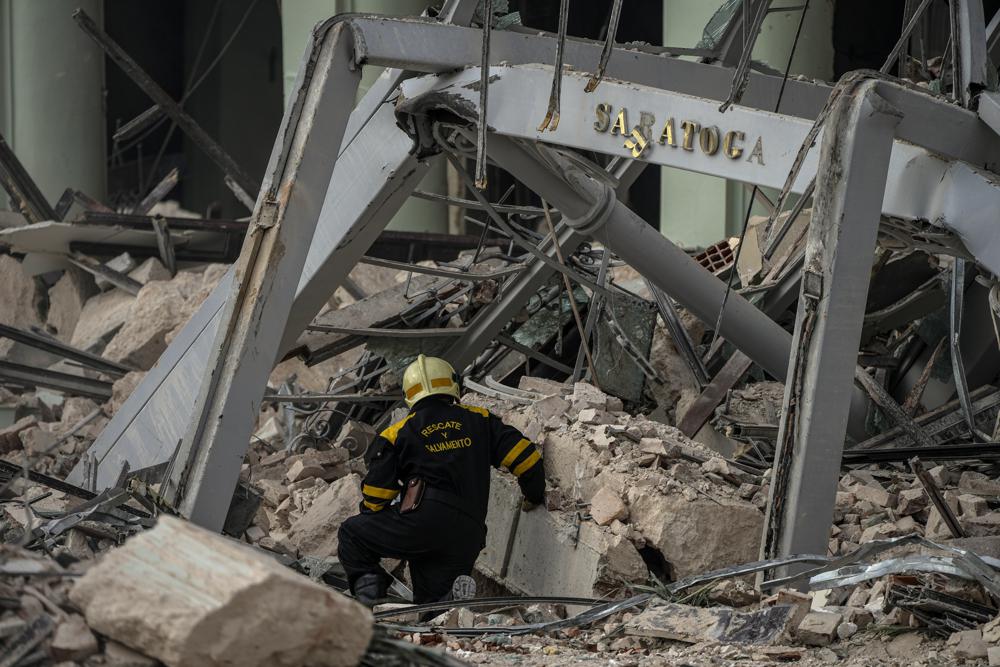 Un miembro de un equipo de rescate busca sobrevivientes en el lugar de una explosión mortal que destruyó el Hotel Saratoga de cinco estrellas, en La Habana, Cuba, el viernes 6 de mayo de 2022. Una poderosa explosión aparentemente causada por una fuga de gas natural mató al menos 18 personas, incluida una mujer embarazada y un niño, e hirió a decenas el viernes cuando voló las paredes exteriores del hotel de lujo en el corazón de la capital de Cuba.  (Foto AP/Ramón Espinosa)