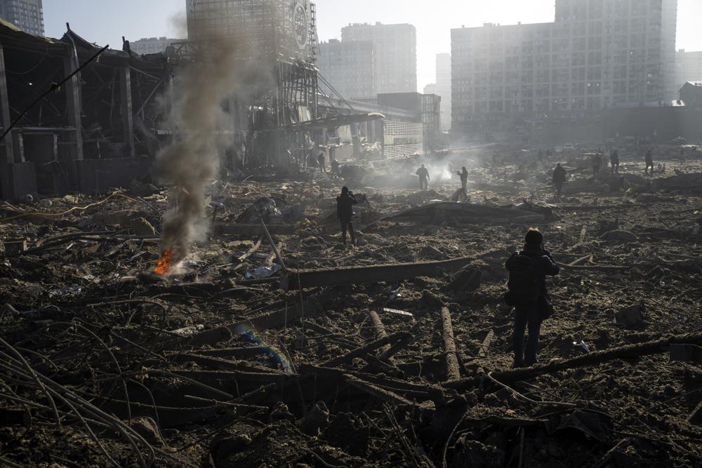 People gather amid the destruction caused after shelling of a shopping center, in Kyiv, Ukraine, Monday, March 21, 2022. (AP Photo/ (AP Photo/Rodrigo Abd)