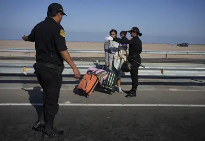 Un migrante venezolano y un niño son detenidos por la policía en Tacna, Perú, el viernes 28 de abril de 2023. (AP Foto/Martín Mejía)